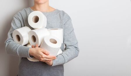 man, a girl holds an armful of toilet paper rolls in his hands. the hype about the demand for toilet paper during the global coronavirus pandemic. studio isolated.の写真素材