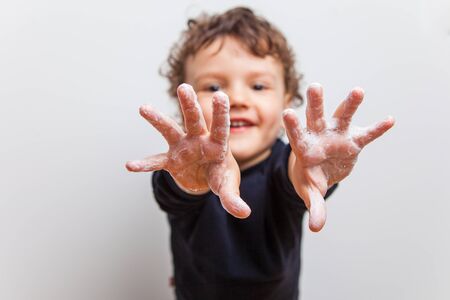 boy, toddler pulls soaped hands forward into the frame. Hygienic procedures, prevention of diseases with viruses and SARS. How to protect yourself from COVID-19. Proper hand washingの写真素材