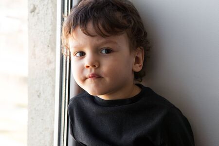 will rub a bored boy in a room by the window. quarantine and isolation during the COVID-19 pandemic....