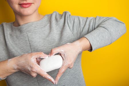 Female hands making sign Heart by fingers holding a bar of soap. washing hands with soap saves life...