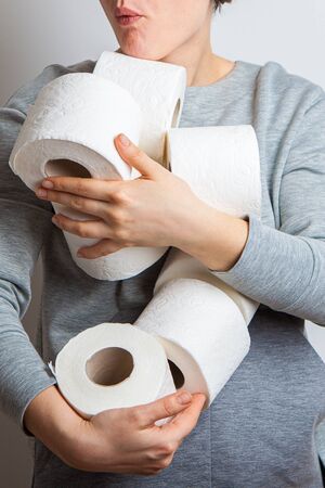 greedy woman holds an armful of toilet rolls. Panic. stocks during the quarantine period of the coronavirus pandemicの写真素材