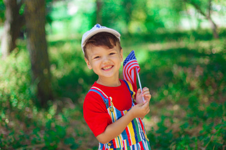 a large portrait of a beautiful child. The boy laughs and smiles in bright clothes, a red T-shirt on the green background of nature. horizontal portrait of happy baby.の写真素材