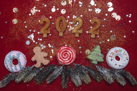 2022 decorative figures of the new year and Christmas, golden candles on a red background. frame of spruce branches. banner, Christmas card,の写真素材