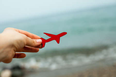 in the hands of a mahogany plane made of wood against the background of the sea coast and sky. a small small plane flies up over the sea and waves. recreation and tourism.の写真素材