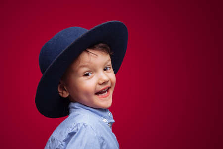 cute happy boy in a blue hat on a red background. the emotional child smiles. Mockup. horizontal.の写真素材