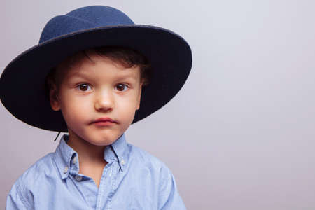 a funny kid in a hat shows his tongue and laughs. in the studio, on a white background, a large portraitの写真素材