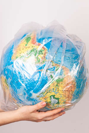 a globe in a plastic bag on womens hands on a white background. Isolated.の写真素材