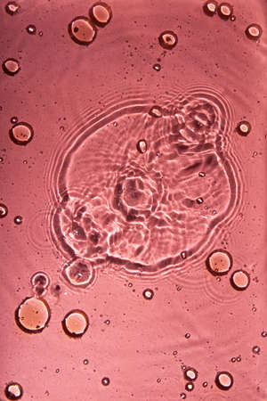 A pattern of pink doses of acid, hyaluronic moisturizing serum or gel on a water background. Abstract backdrop pattern. Cosmetics or healthcare protection conceptの写真素材