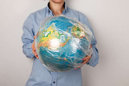 a woman holds a globe of planet earth in a plastic bag. without a face.の写真素材