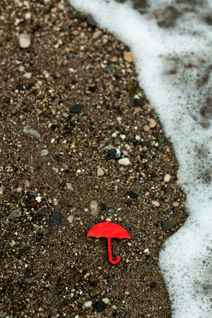 a red wooden figure of an umbrella against the background of the sea and the waves. weather...