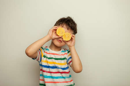 funny boy with lemons in a striped T-shirt on a white background.の写真素材