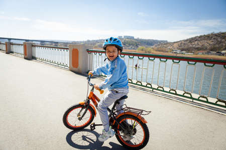a happy smiling boy on a bicycle in a blue jacket and helmetの写真素材