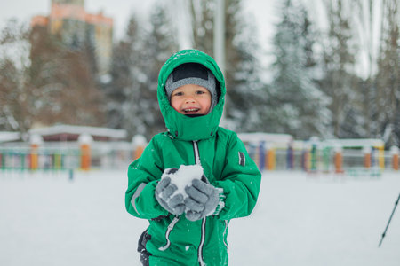 the boy carries snow in his hands. Winter Games. a little boy plays outside in the winter. boy smiling.の写真素材