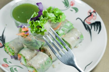 Portion of spring rolls on old wood with spicy sauce, vegetables and in noodle tubeの写真素材