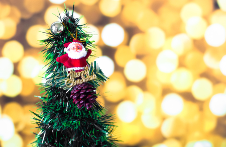Santa Claus doll against pine nut with ball and Christmas tree on yellow bokeh light backgroundの写真素材