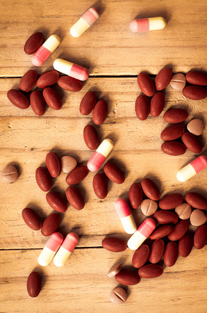Pill spilling out on old wood backgroundの写真素材
