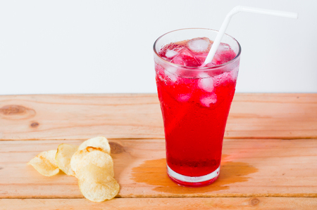 red drinks with soda and ice in glass with straw and fired potato on wooden backgroundの写真素材
