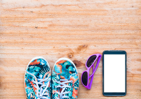 Canvas shoe with sunglasses and mobile phone on wooden background. accessories for travellingの写真素材