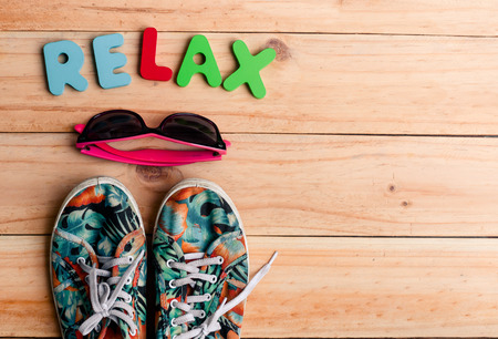 colorful canvas shoe and sunglasses with RELAX alphabet on wooden background. accessories for travelling. copy spaceの写真素材