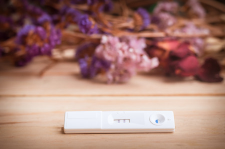 pregnancy test and dried flowers on wooden background. process dark toneの写真素材