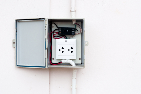 modern breaker switch and white plug are hang on cement background