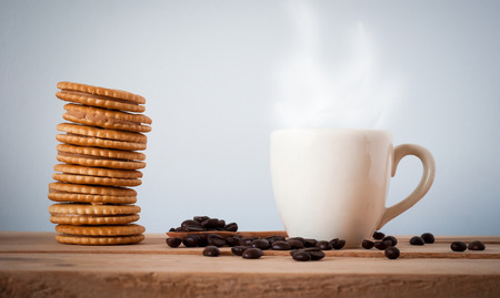 coffee beans and cup of coffee with cracker on wooden table background. coffee breakの写真素材