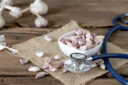 Big garlic among seed garlic and stethoscope on old wooden table with big garlic backgroundの写真素材