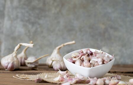garlic in bowl on old wooden table with big  garlic backgroundの写真素材