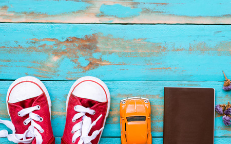 red sneakers with orange car and passport book on old blue wooden floor background. copy space for graphic designerの写真素材