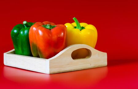 Summer of sweet bell pepper in wood box on red backgroundの写真素材