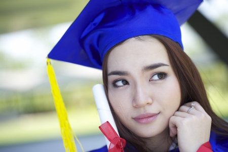 portrait of a beautiful young asian woman in graduation cap, sorrow in campusの写真素材