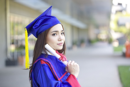 portrait of a beautiful young asian woman in graduation cap in campusの写真素材