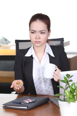 asian businesswoman sitting in office, looking tired and stress, with medicine pillsの写真素材