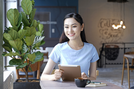 Asian pretty attractive woman sitting in coffee shop using smart phoneの写真素材