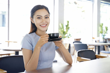 Asian pretty attractive woman working on laptop computer in coffee show with bright optimistic backgroundの写真素材