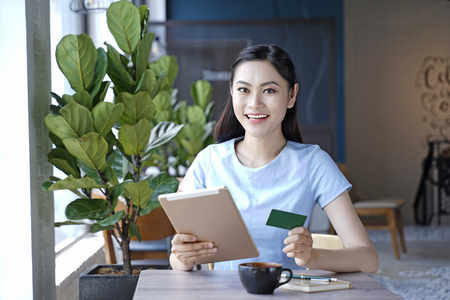 Asian pretty attractive woman sitting in coffee shop using smart phoneの写真素材