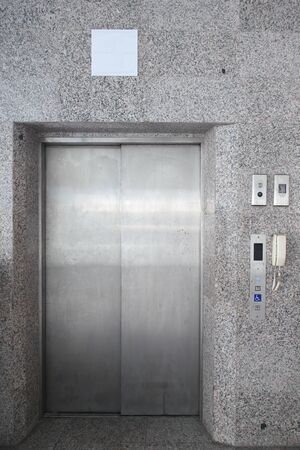 Lift or elevator metal doors white sign with marble wall building.