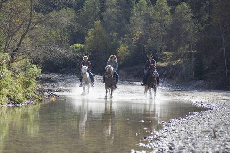 Austria, Salzburger Land, Altenmarkt, Young people riding horses across riverの写真素材