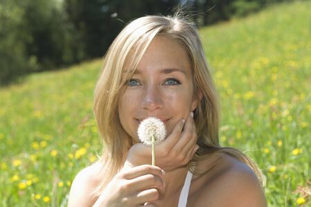 Austria, Salzburger Land, Young woman holding blowball, close upの写真素材