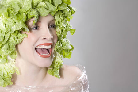 Young woman with lettuce on head, portraitの写真素材