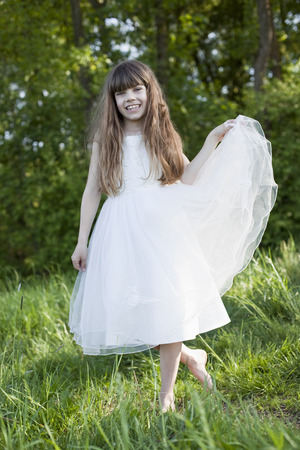 Germany, Bavaria, Girl in meadow lifting dress, smilingの写真素材