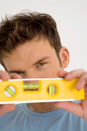 Young man with yellow spirit level, close-up