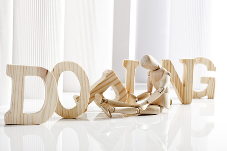 Symbolic for doping, Wooden figurine sitting in front of wooden lettersの写真素材
