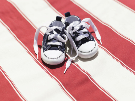 Baby shoes on striped clothの写真素材