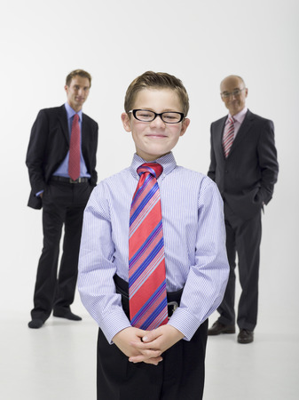 Boy standing in business attire with father and grandfatherの写真素材