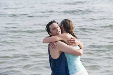 Spain, Mallorca, Couple embracing in ocean in clothes wet