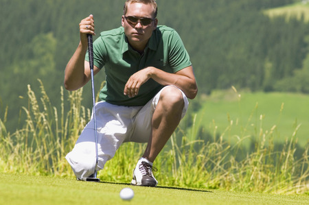 Golf player on golf course, squattingの写真素材