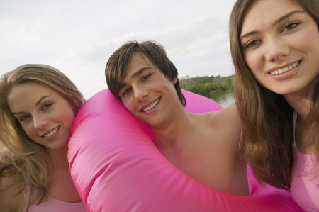 Three young people with rubber ring, smilingの写真素材