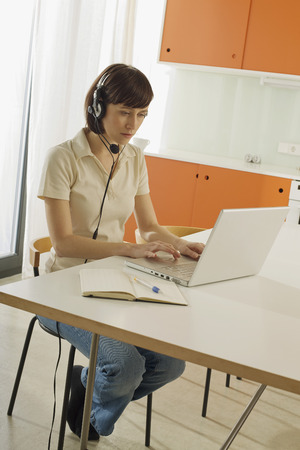 Young woman using laptop wearing headsetの写真素材