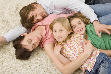 Family lying on floor in living roomの写真素材